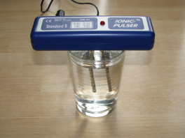 Der Silberionengenerator
                  (englisch: "ionic pulser") auf einem Glas
                  Wasser mit den Silberst�ben im Wasser