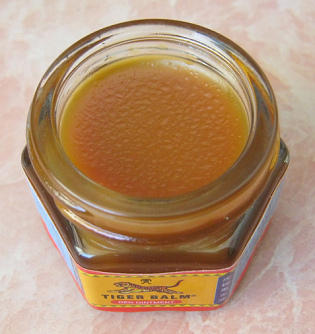 Glass of
                    tiger balm without tap showing the red tiger balm