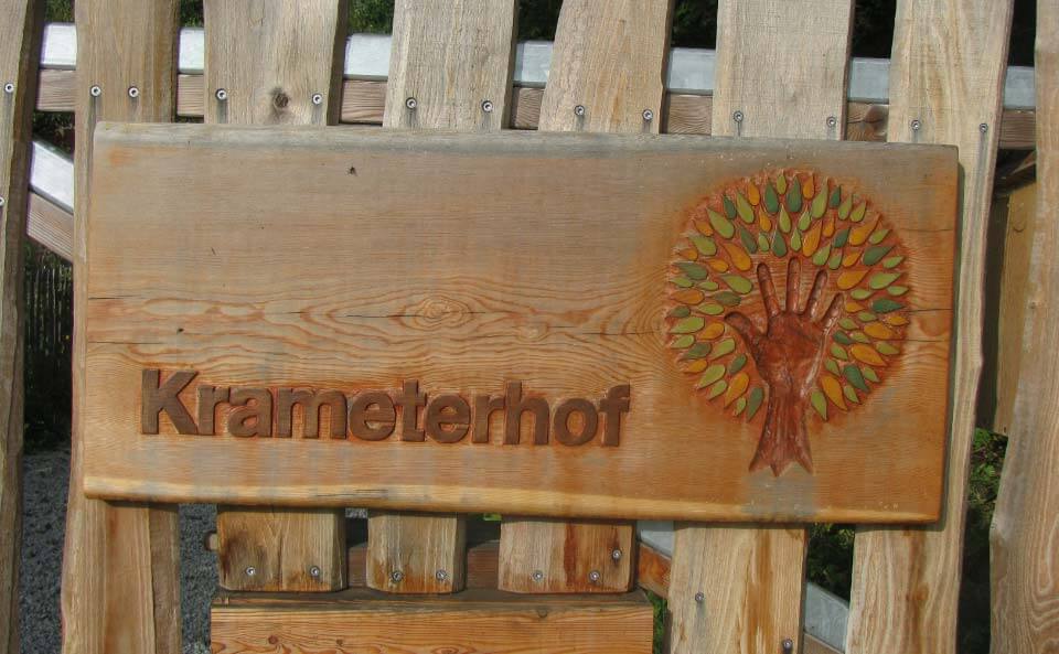 Das
                    Eingangsschild "Krameterhof" aus Holz mit
                    einem Hand-Baum