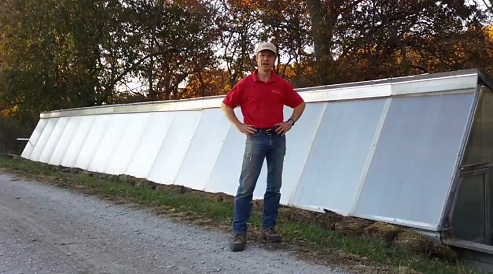 Farmer at his pit greenhouse in
                                  front of the solar window front