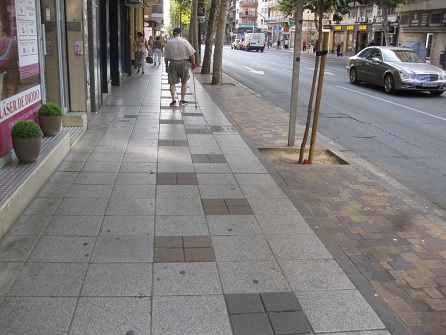 Trottoir
                        / B�rgersteig in weissen Platten mit schwarzen
                        Tupfern, und Baumbereiche in gelb-rot-schwarzen
                        Gartensteinen