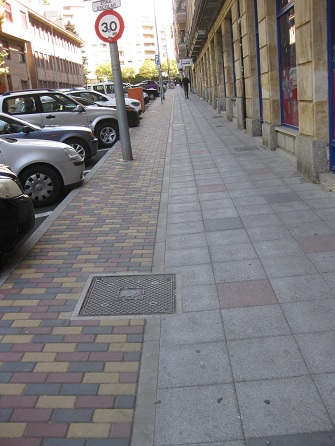 Trottoir in Platten: Weiss
                    mit roten Tupfern - und der Randbereich in
                    Gartensteinen gelb-rot-schwarz
