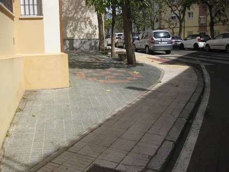 Kleiner Platz mit gr�nen
                        Gartensteinen, rotem Muster und gelbem Trottoir
                        in gerillten Platten