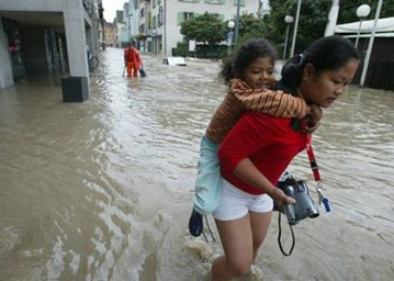 Hochwasser
                        Schweiz 2005 Sarnen: Touristin im Hochwasser mit
                        Kind auf dem R�cken; flood inondation