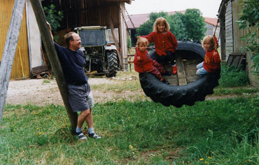Tire swing 18 with
                            installed wooden bottom and with a swinging
                            person outside, vacation farm Meyer in
                            Geslau, Franconia, Germany