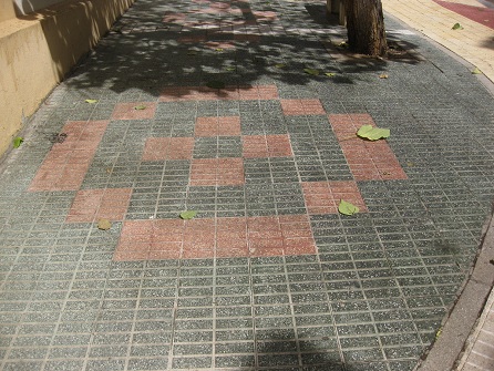 Kleiner Platz mit grünen Gartensteinen, rotem
Muster und gelbem Trottoir in gerillten Platten,
Zoom Kleiner Platz mit grünen Gartensteinen,
rotem Muster und gelbem Trottoir in gerillten
Platten, Zoom