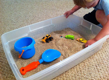 Sandkasten im Haus 02,
                            Kiste mit Sand, Spielautos und Spielbagger
                            und Schaufel